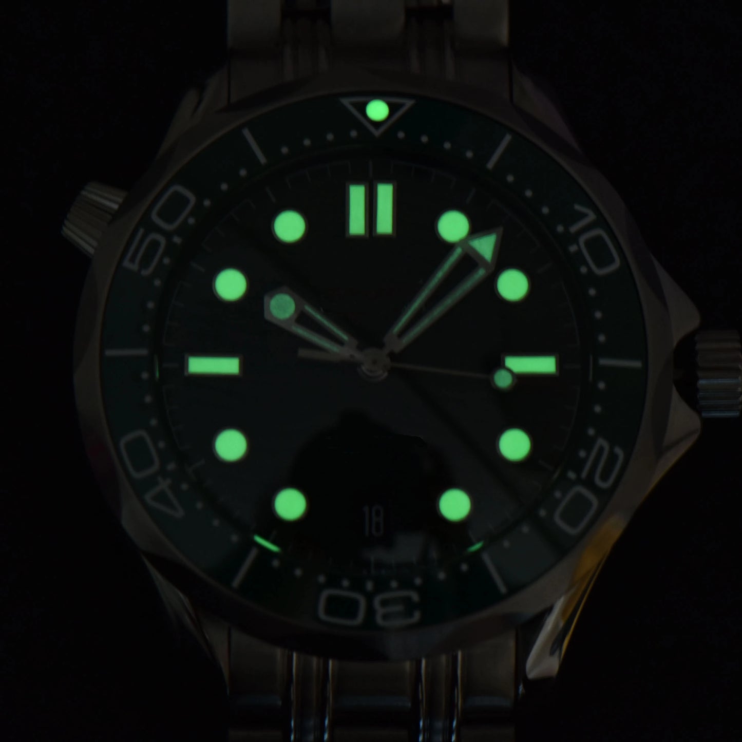Luminous green dial and hands of Seamaster style Seiko mod diver watch in dark environment