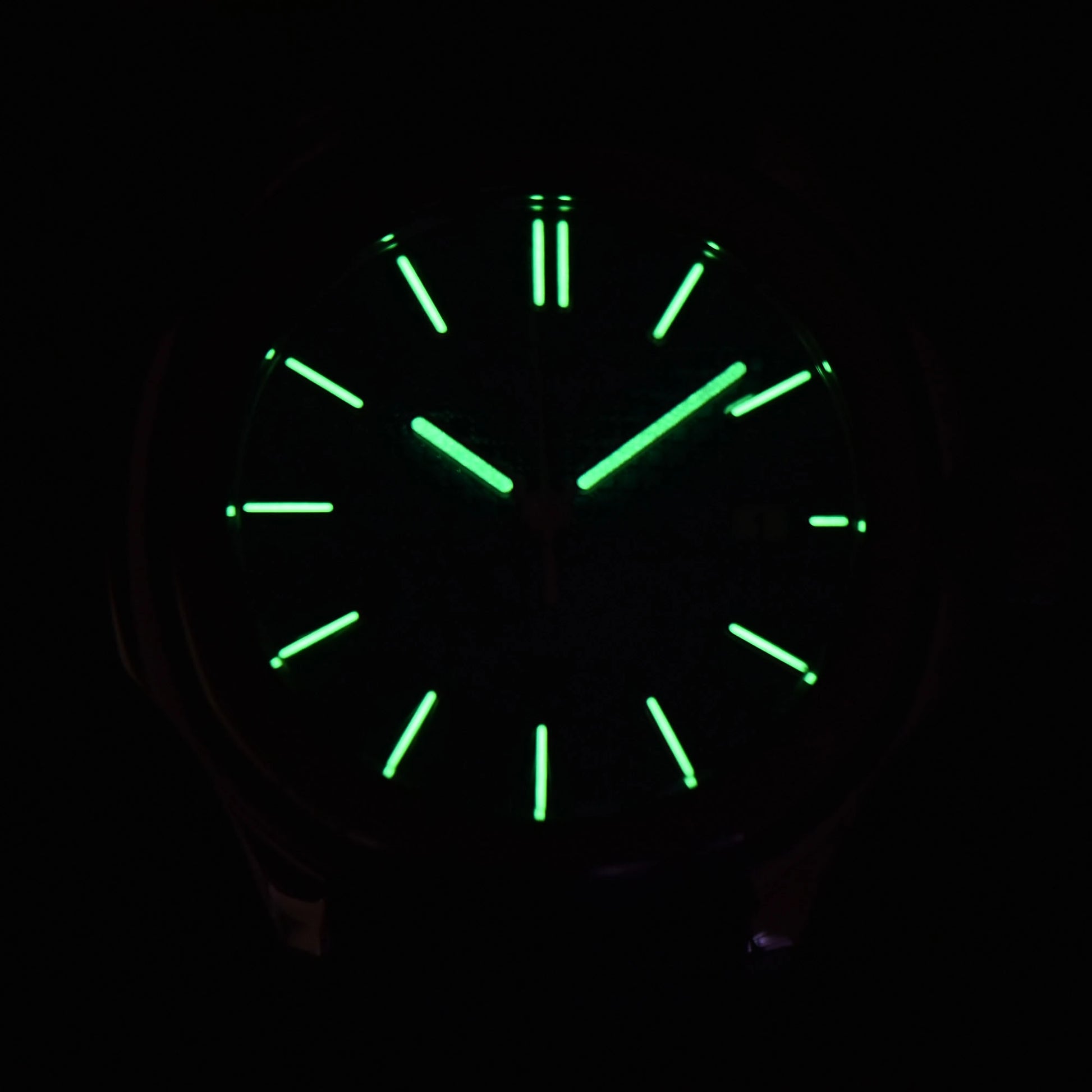 Low light close-up of Seiko mod watch dial showing strong C3 Super-LumiNova on custom hands and indices