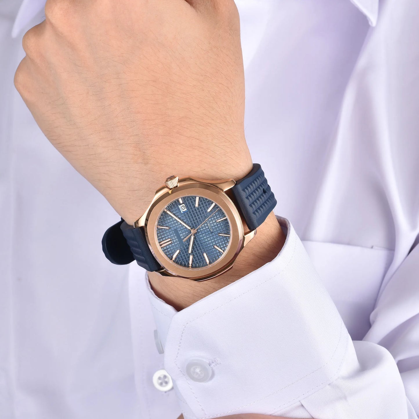 Rose gold Aquanaut style Seiko mod watch with blue rubber strap on wrist, business lifestyle shot
