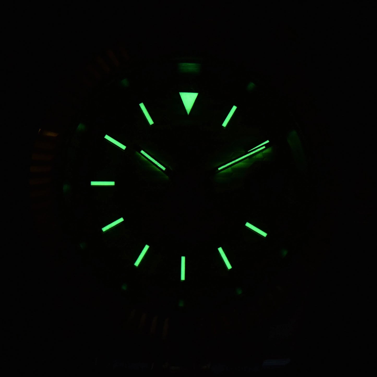 Low light close-up of Seiko mod watch dial showing strong C3 Super-LumiNova on custom hands and indices
