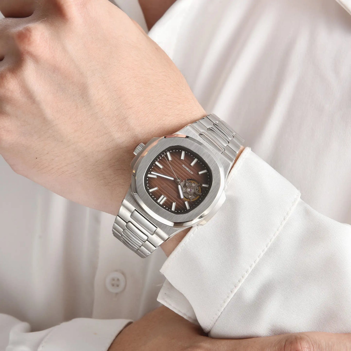 Open heart brown Nautilus style Seiko mod watch with stainless steel bracelet on wrist, business lifestyle shot