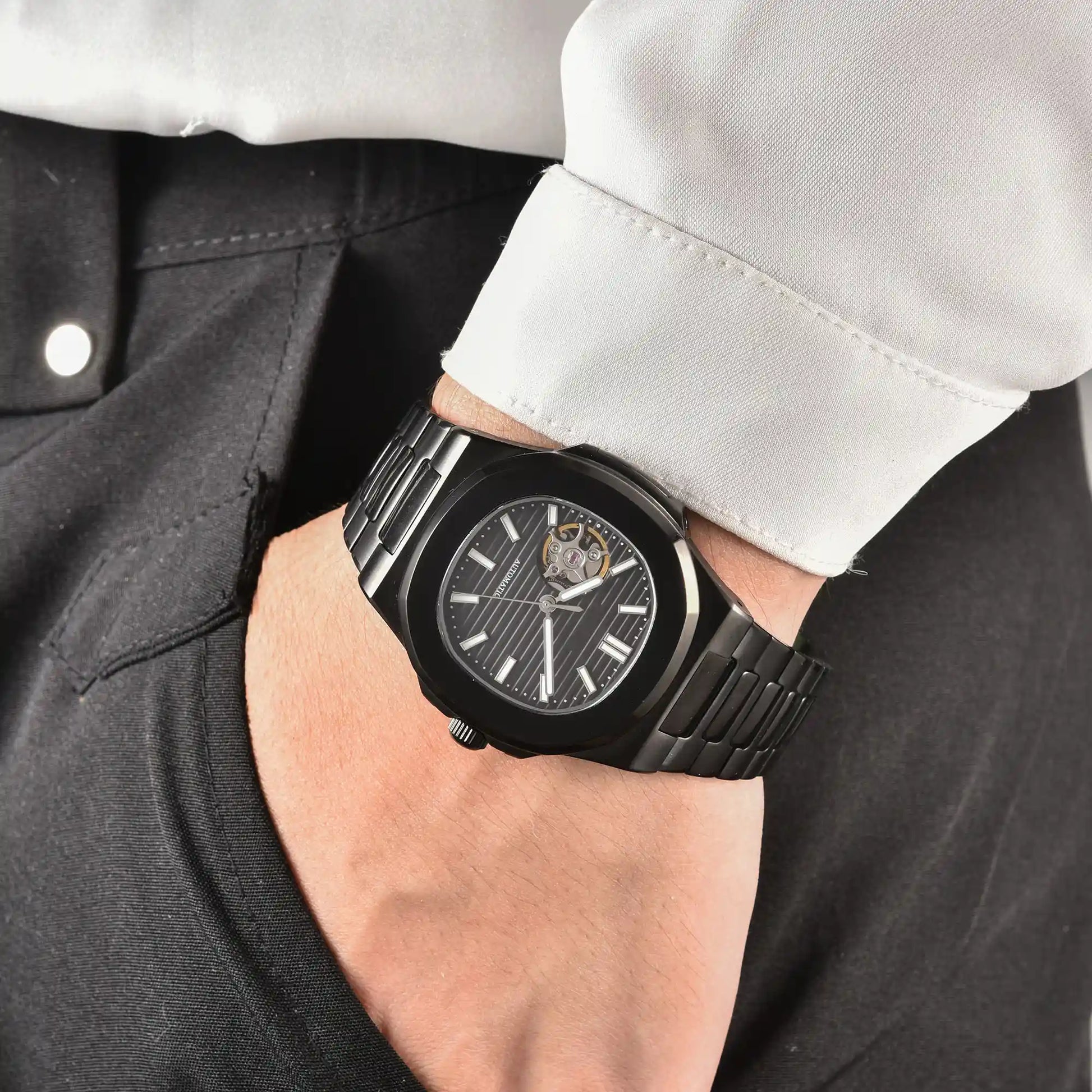 Men's full black open heart dial Nautilus style Seiko mod watch on wrist, casual daily wear lifestyle shot