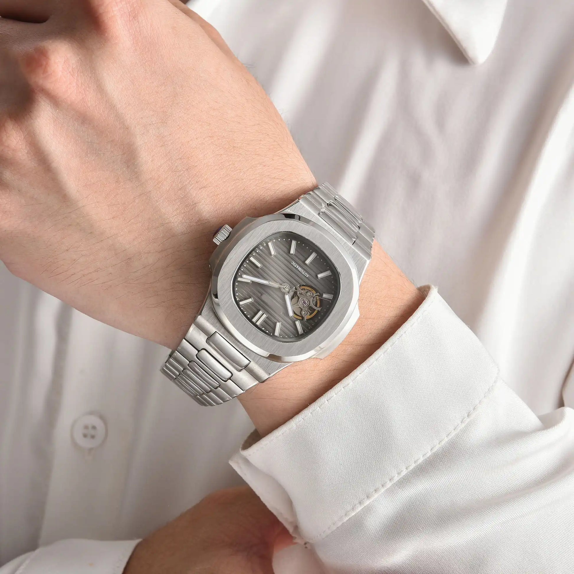 Open heart gray Nautilus style Seiko mod watch with stainless steel bracelet on wrist, business lifestyle shot