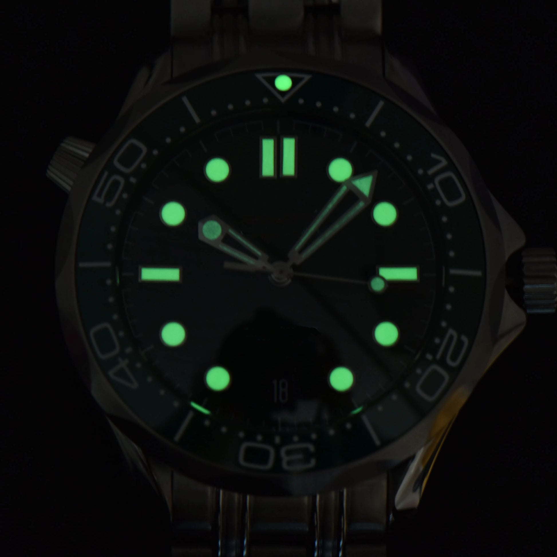 Luminous green dial and hands of Seamaster style Seiko mod diver watch in dark environment