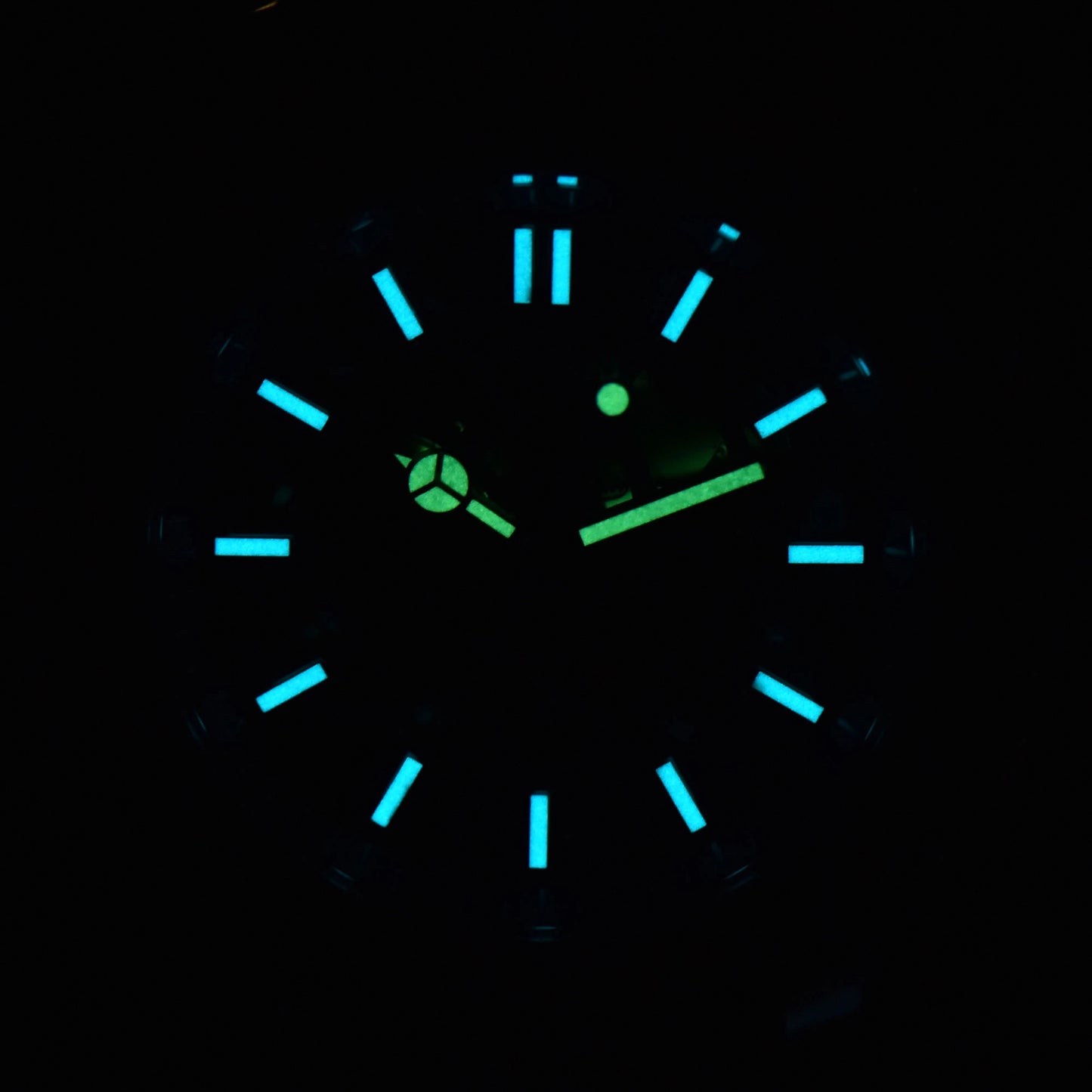 Luminous blue-green dial and hands of skeleton Aquanaut style Seiko mod watch in dark environment