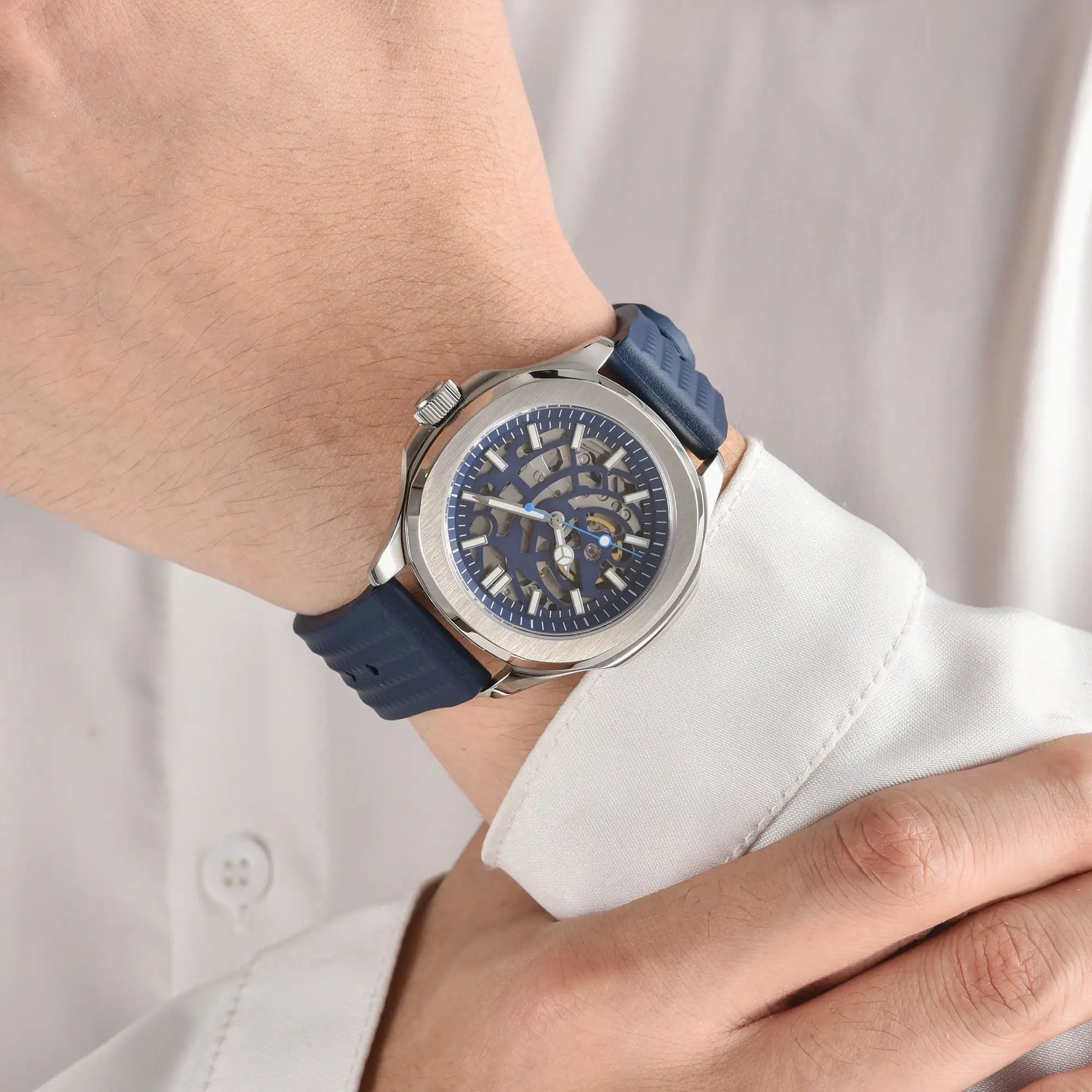 Skeleton Aquanaut style Seiko mod watch with blue rubber strap on wrist, business lifestyle shot